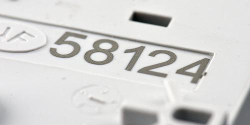 Incisione laser su plastica su una parte bianca che mostra numeri di serie ad alto contrasto