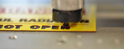 Materiale per incisione Gravoply™ 3C in fase di incisione con testo di sicurezza